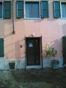 a pink building with a door and two potted plants at B&B Medole in Medole