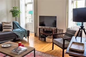 a living room with a couch and a flat screen tv at Janelas Verdes Apartments in Lisbon