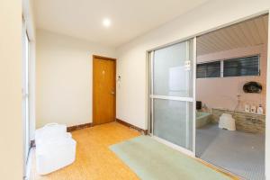 an empty room with a glass door and a bathroom at 柏屋旅館＜シェアハウス&ゲストハウス＞ in Saku