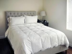 a bedroom with a white bed with a white comforter at Bricco Suites in Boston