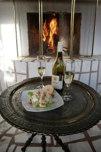 einen Tisch mit einem Teller Essen und zwei Gläsern Wein in der Unterkunft Castle Cottage Bed & Breakfast in Belogradtschik
