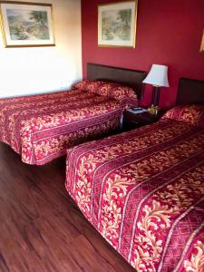 2 bedden in een hotelkamer met rode muren bij Cajun Inn Motel in Galliano