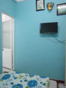 a bedroom with a blue wall with a tv on the wall at Bình An in Da Lat