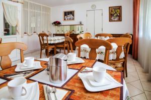 a dining room with a table with white dishes and chairs at Kata Panzió in Szeged