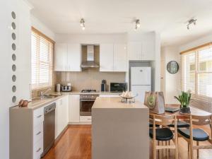 a kitchen with white cabinets and a table with chairs at BOUTIQUE STAYS - Sandy Breeze 3 in Sandringham