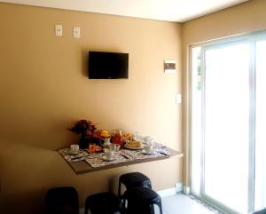 a table in a room with a tv on a wall at Casa 1 dormitório prox da praia in Itapema