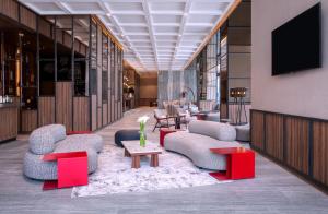 a lobby with couches and tables and a tv at Mercure Jakarta Pantai Indah Kapuk in Jakarta