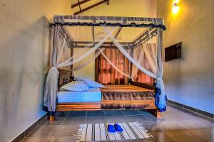 a bedroom with a canopy bed with blue shoes on the floor at Dambulla Hills Resort in Dambulla +18 photos