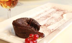 a chocolate cake on a plate next to a glass of wine at Hotel Clipper - EL DELFÍN VERDE RESORTS - Platja de Pals in Torroella de Montgrí