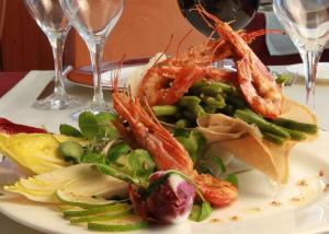 a plate of food with shrimp and vegetables on a table at Hotel Clipper - EL DELFÍN VERDE RESORTS - Platja de Pals in Torroella de Montgrí