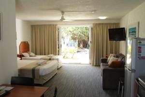 a hotel room with two beds and a couch at Whitehaven Beachfront Holiday Units in Airlie Beach