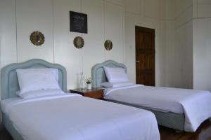 two beds in a room with white sheets at Mesilau Mountain Retreats in Kundasang
