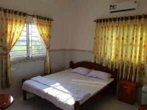 a bedroom with a bed and a window with curtains at Minh Kim Guesthouse in Ấp Phó