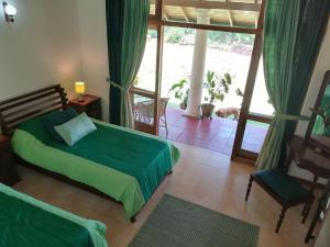 una camera con un letto verde e una grande finestra di Jungle Tide a Kandy
