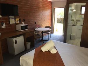 a hotel room with a bed with a microwave and a table at Pooraka Motor Inn in Mawson Lakes