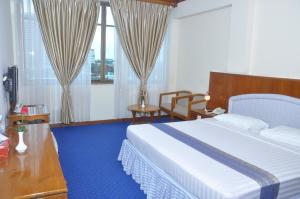 Habitación de hotel con cama, escritorio y ventana en Panorama Hotel, en Yangón