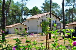 a child riding a bike in front of a house at Résidence Goélia Les Demeures du Lac in Casteljaloux