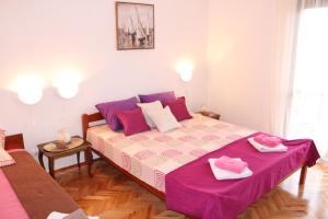 a bedroom with a large bed with pink and purple sheets at Guest House Tomanovic in Herceg-Novi