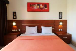 a bedroom with a bed with an orange blanket at Kondra Premiere Guest House Kuta in Kuta