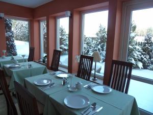 a dining room with tables and chairs and windows at Siedem Świerków in Szczecinek