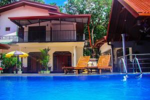 a swimming pool with two chairs next to a house at Sevonrich Holiday Resort in Dambulla