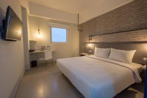 a bedroom with a white bed and a brick wall at Hotel 88 Bekasi By WH in Bekasi