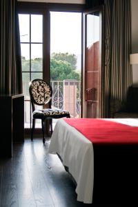 a bedroom with a bed and a chair and a window at Hotel Canal Olímpic in Castelldefels