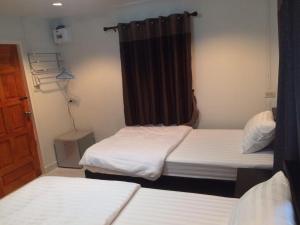 Cette petite chambre comprend 2 lits et une fenêtre. dans l'établissement Baan Phu Jad Kan, à Uttaradit