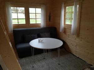 een tafel en een bank in een kamer met ramen bij Hjemstavnsgårdens Camping & Cottages in Glamsbjerg