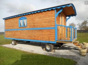 ein kleines Holzhaus auf einem Anhänger auf einem Feld in der Unterkunft La Canfouine in Lamballe