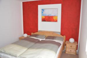 a bedroom with a bed and a red wall at Ferienwohnung Römerbrücke in Trier