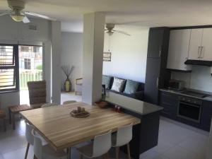 a kitchen and dining room with a wooden table at Umdloti Cabanas 21 Triplex in Umdloti