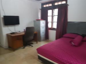 a bedroom with a bed and a desk and a computer at Mayestik Guest House Syariah in Jakarta