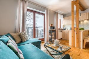 a living room with a blue couch and a kitchen at Apartament Marmurki Zakopane in Zakopane