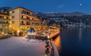 ein großes Gebäude neben einem Gewässer in der Unterkunft SEEGLÜCK Hotel Forelle Superior in Millstatt