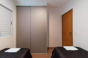 a bedroom with two beds and a closet at Apartamento Moderno Poços de Caldas in Poços de Caldas