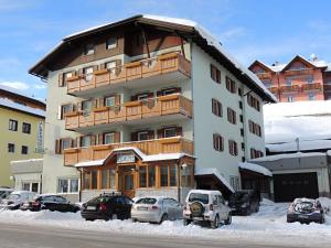 a large building with cars parked in the snow at Albergo Eden in Passo del Tonale