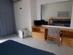 um quarto com uma secretária, uma cama e um espelho. em Hotel Neptuno em Oropesa del Mar