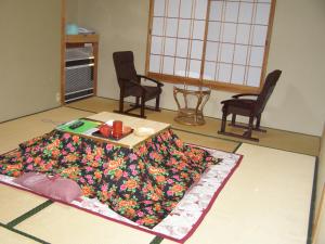 een woonkamer met een tafel en een bloemkleed op de vloer bij Kadowakikan in Nozawa Onsen