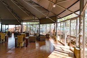 um átrio com mesas, cadeiras e janelas em Waterberg Wilderness - ONE Namibia em Waterberg