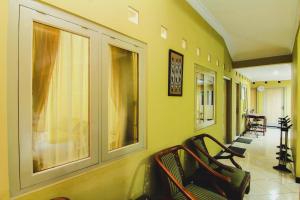 um corredor com duas cadeiras e paredes amarelas em Griya Batik Giri Sekar Homestay em Yogyakarta