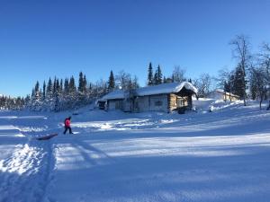a person walking in the snow in front of a cabin at Aurora Nova in Koskullskulle