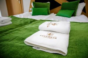 two beds with green sheets and white towels on them at Estancja Mezowo in Mezowo