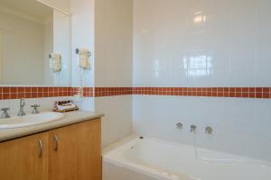 een badkamer met een wastafel en een bad bij Canning Bridge Auto Lodge in Perth