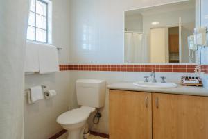 een badkamer met een toilet, een wastafel en een spiegel bij Canning Bridge Auto Lodge in Perth
