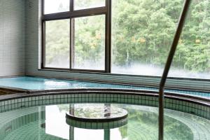 ein Schwimmbad in einem Gebäude mit einem großen Fenster in der Unterkunft Hotel Tagawa in Yamanouchi