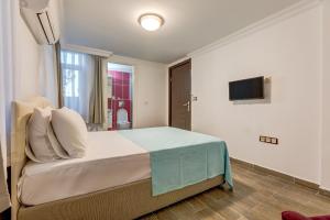 a bedroom with a bed and a tv on the wall at Nefes Hotel in Ayvalık