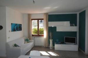 een woonkamer met een witte bank en een televisie bij Villa Fiori in Malcesine
