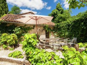 una mesa y sillas con sombrilla frente a una casa en Cosy Holiday Home in Bourgnac with Private Pool, en Bourgnac