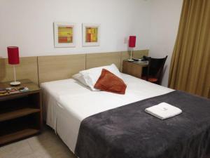 a hotel room with a bed with a red pillow on it at Camboinhas Beach Pousada in Niterói